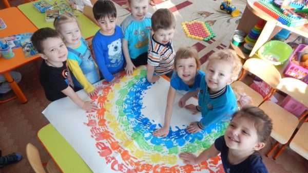 Дети из отпечатков ладошек делают рисунок радуги