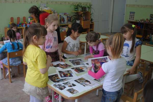Девочки рассматривают фотографии с людьми разных национальностей