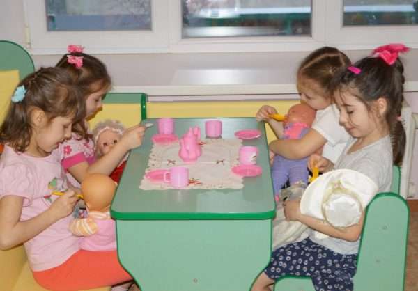 Девочки кормят кукол-младенцев в кафе