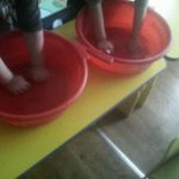 Два ребёнка делают пальчиковую гимнастику в красных тазах с водой