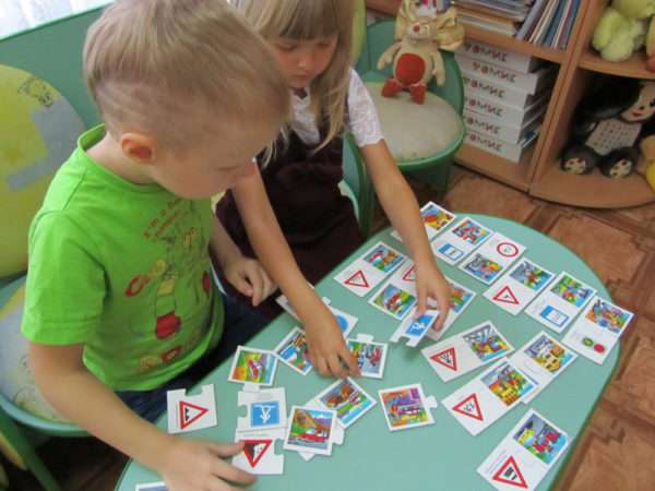 Две детей складывают карточки со знаками ПДД