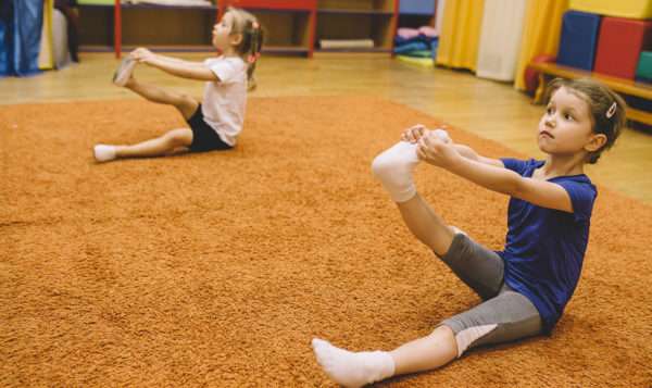 Две девочки тянут ножки на ковре