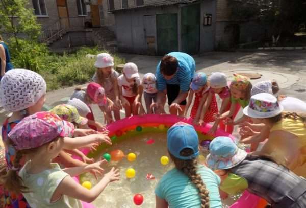 Дети ловят руками шарики в надувном бассейне