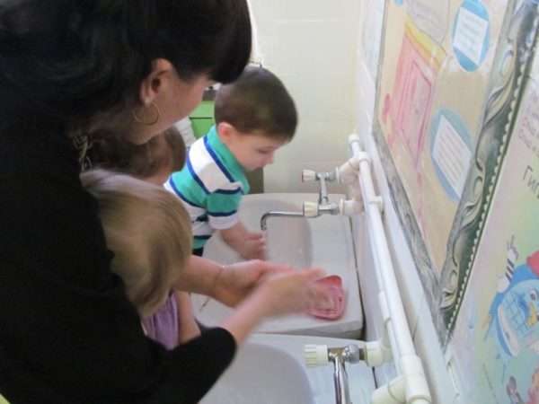 Воспитатель вместе с детьми моет руки