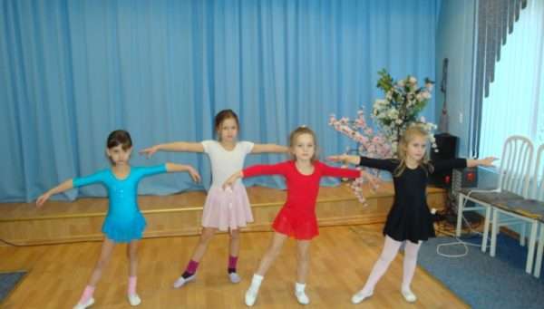 Четыре девочки выполняют танцевальное движение
