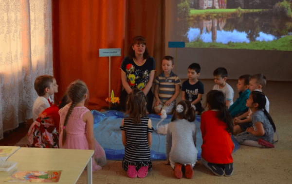 Дети и воспитатель сидят на полу вокруг «Озера доброты»