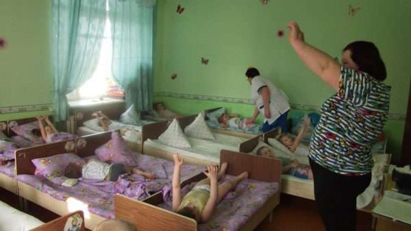 Дети выполняют гимнастику в кроватях, педагог показывает движения