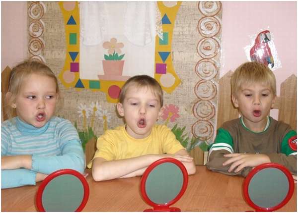 Трое детей произносят звук «О» перед зеркалами