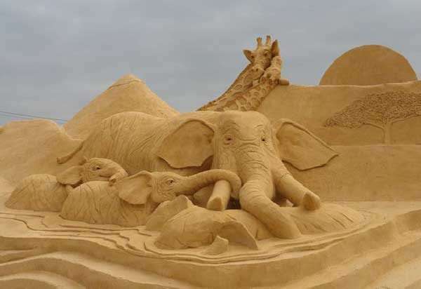 Фигуры слонов и жирафов из песка