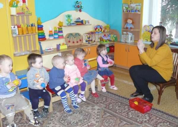 Воспитательница, сложив ладони вместе вверх, показывает детям пальчиковое упражнение