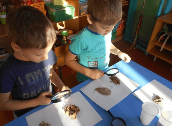 Мальчики изучают состав песка при помощи увеличительных стёкол