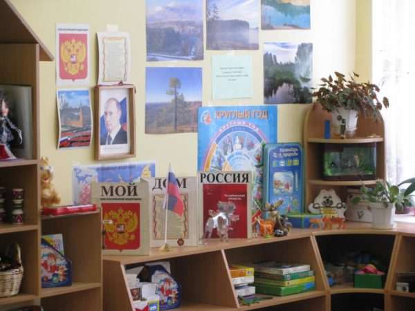 Уголок патриотического воспитания с портретом Путина, книгами Мой дом Россия, справа на картинках пейзажи