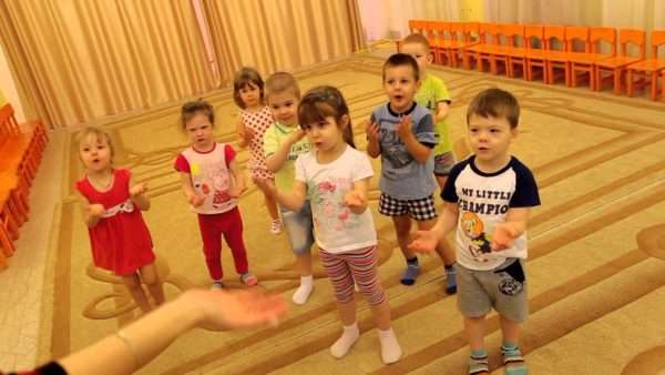 Малыши делают движения руками, подражая педагогу