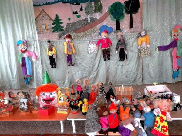 Театральный уголок с разными куклами на столах и на ширме