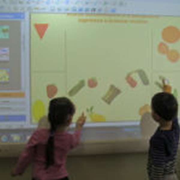 Два ребёнка распределяют предметы по группам на интерактивной доске