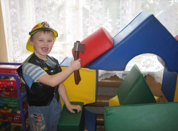 Мальчик в жёлтой каске играет в строителя