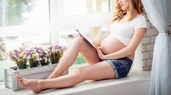 Беременная девушка читает книгу