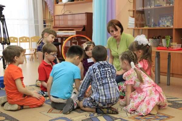 Дети и педагог сидят на ковре в кругу