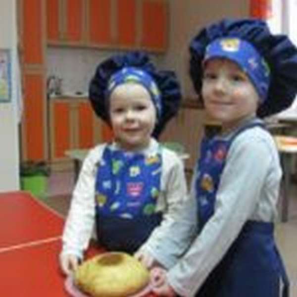 Две девочки держат в руках тарелку с испечённым караваем
