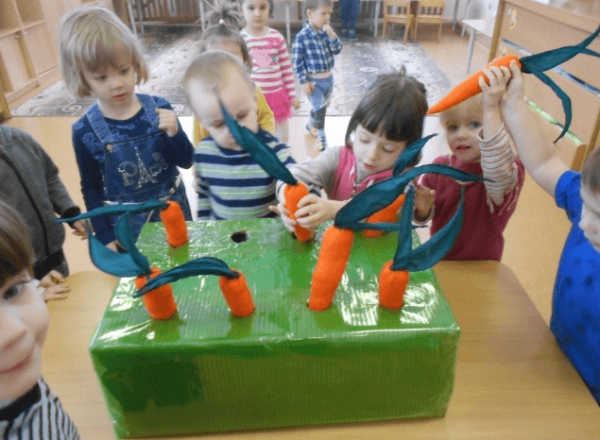 Дети вытаскивают муляжи морковок из зелёной коробки
