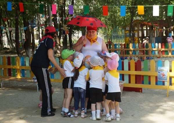 Дети под зонтиком-мухомором с воспитательницей