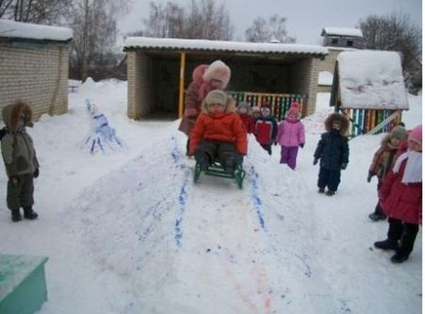 Ребёнок едет на санках по снежной горке, остальные дети наблюдают