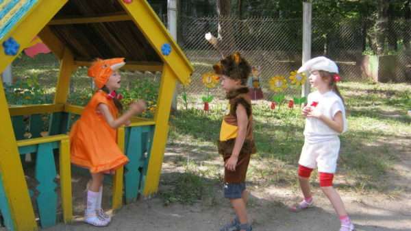 Дети в костюмах лисички, медведя и зайца во дворе рядом с домиком-бесед