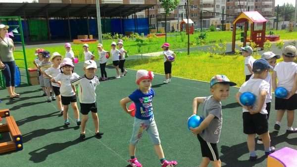 Дети на площадке выполняют упражнение с мячами