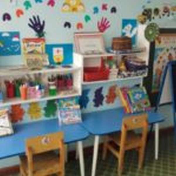 Центр творчества, синие столики, деревянные стулья, на полочках над столами материалы и готовые рисунки