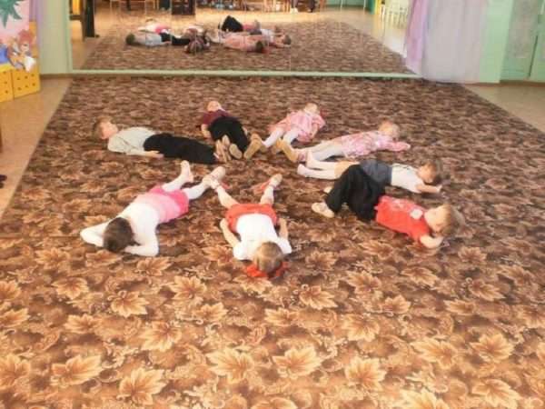 Дети лежат на ковре в музыкальном зале