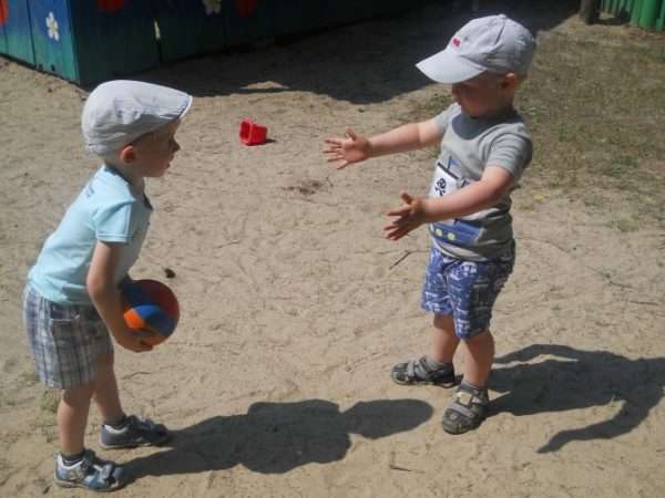 Два мальчика играют на улице в мяч