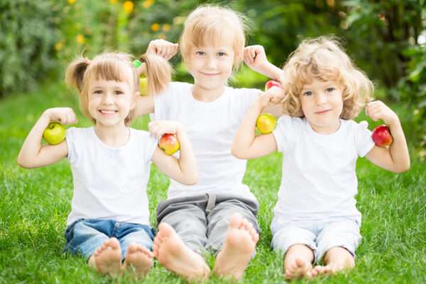 Дети держат яблоки и улыбаются