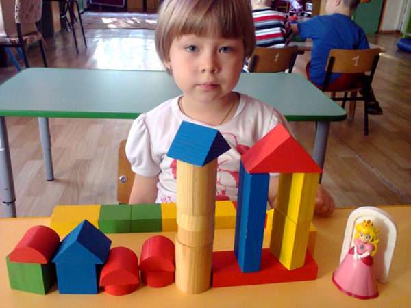 Девочка построила небольшой город из строительного материала для куклы